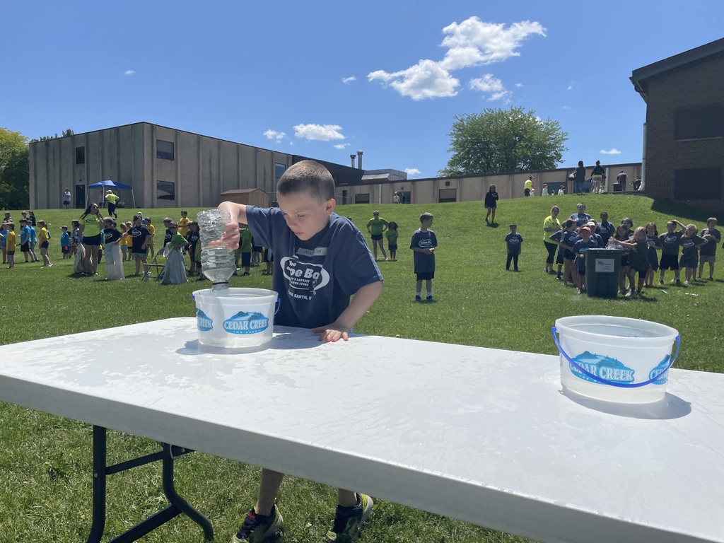 student in grey shirt dumping water into bucket on field day