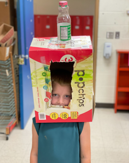 Boy with his head inside a box and a plastic bottle on top