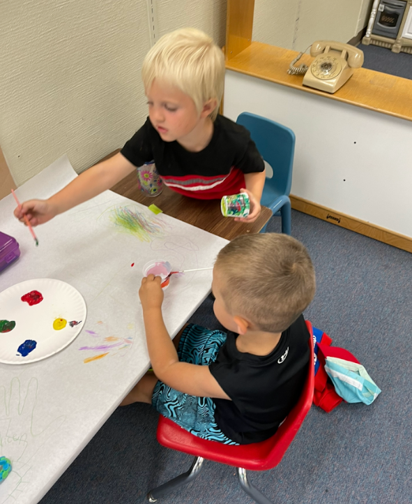 Two boys with a plate of paint and paintbrushes