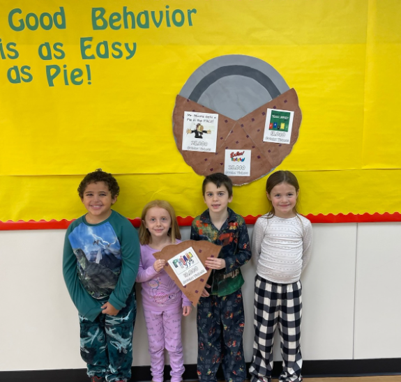 4 elementary students standing in front of good behavior pie